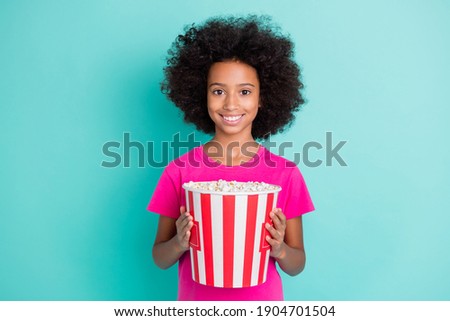 Photo portrait of black skin girl holding bucket of popcorn isolated on vivid cyan colored background