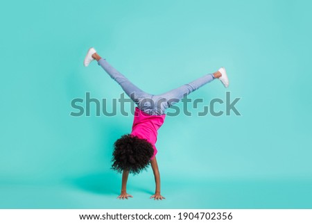 Full length photo portrait of black skin girl standing on hands isolated on vivid cyan colored background