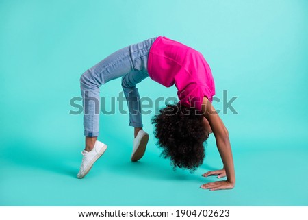 Full length photo portrait of black skin girl standing in bridge pose isolated on vivid cyan colored background