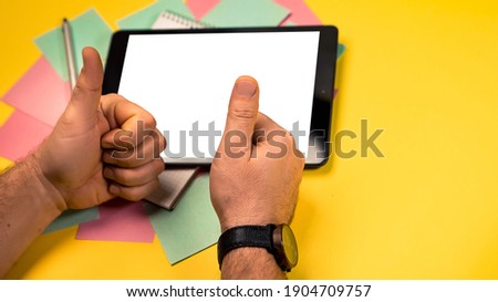Cropped view mock up image black tablet pc white blank screen isolated yellow background. Colorful memo sticky pin clips empty notes scattered chaotic manner. Man showing thumbs up wrist watch
