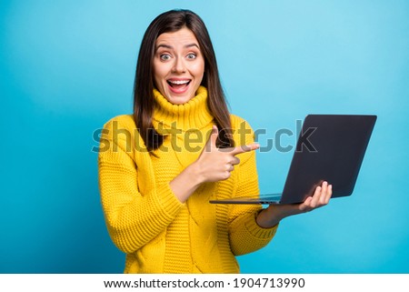 Photo of pretty shocked young woman dressed yellow pullover pointing finger modern device isolated blue color background