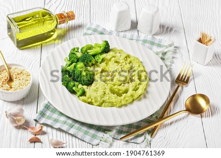 broccoli potato mash sprinkled with chopped almonds served with steamed broccoli florets on a plate on a white wooden table, horizontal view from above