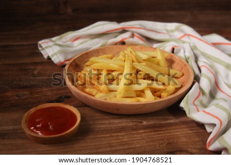 Crispy french fries on wooden plate with chili sauce. Diet food to replace carbohydrates from rice. Served with a napkin. Selective focus photo