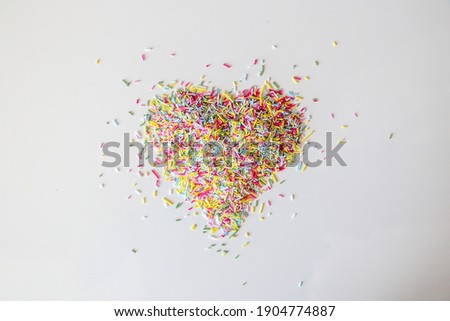 Colourful sprinkles in a heart shape on a white background.
