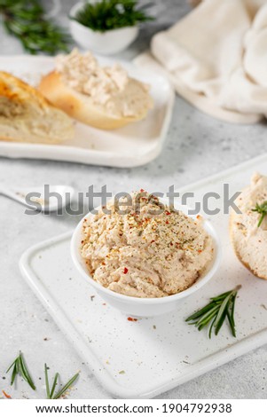 Chicken pate in a white bowl on a light gray kitchen table. Homemade chicken fillet pate with seasonings on a light background