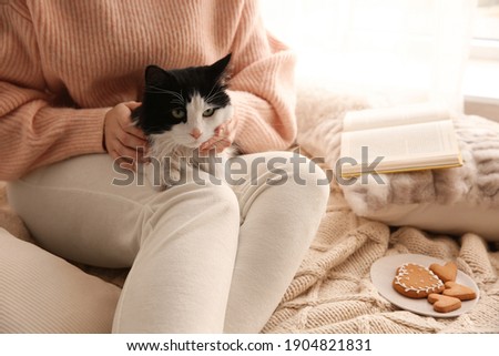 Woman stroking adorable cat on bed, closeup