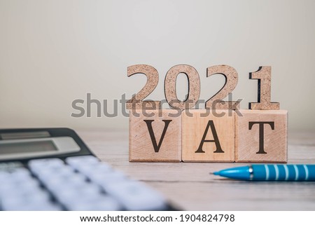 VAT 2021 on wooden cubes, calculator and a pen on a wooden table. VAT 2021 - phrase from wooden blocks with letters, VAT 2021 concept Royalty-Free Stock Photo #1904824798