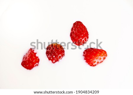 Close-up picture of strawberries floating on the milk surface