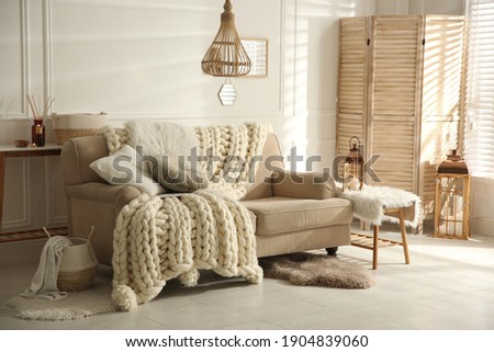 Cozy living room interior with beige sofa, knitted blanket and cushions Royalty-Free Stock Photo #1904839060