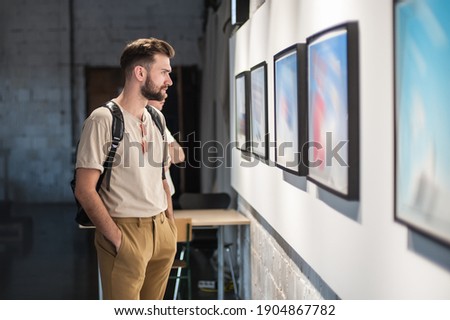 Young man in modern art exhibition gallery hall contemplating artwork. Abstract painting Royalty-Free Stock Photo #1904867782