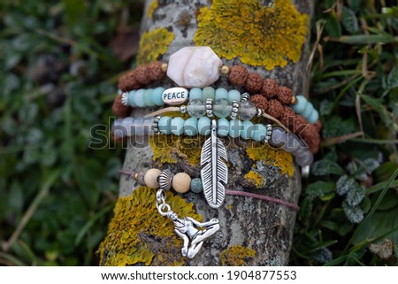 collection of tiny mineral stones bracelets on wooden stick natural background