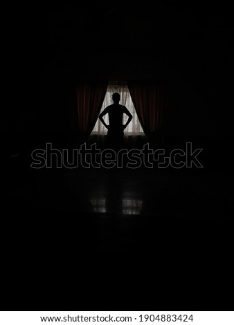 A person silhouette near Window, black and white, loneliness, shadow, vintage, illuminated, abstract, concept.