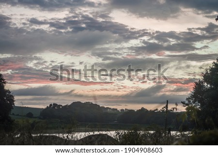 Sunrise with clouds, grass and lake and mountains