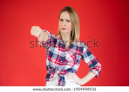 Young caucasian woman isolated on red background showing thumb down