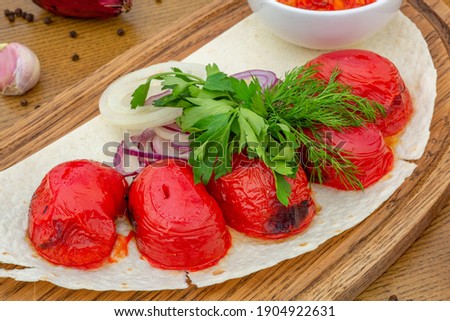 grilled tomatoes with parsley on a wooden board