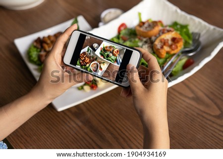 The woman hand is using a mobile phone to take a picture of food on the dining table in the restaurant.  Photography with Mobile Phone Concepts