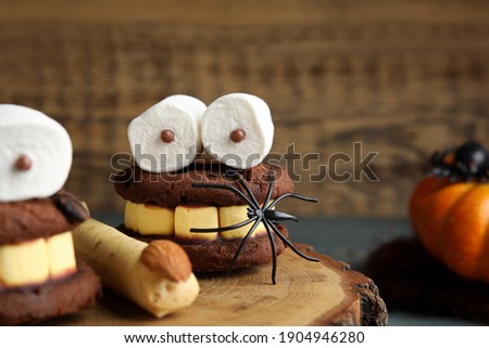 Delicious desserts decorated as monsters on stump, closeup. Halloween treat