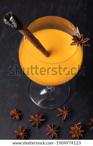 Orange cocktail with aniseed and burnt cinnamon stick on black slate   
