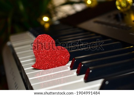 Abstract blurred bokeh on red background. Red heart on piano keys, keyboard close up. Concept of love, valentine's day. Love background. Music lessons, piano. Music day.  