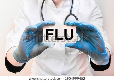 The doctor's blue - gloved hands show the word FLU - . a gloved hand on a white background. Medical concept. the medicine