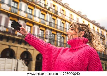 Young caucasian blonde woman taking a selfie on the street