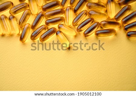 Omega-3 Fish Fat Oil Capsules. Fish oil capsules isolated on yellow background. Close up of capsules Omega 3 on yellow background. Health care concept. Nutritional supplements. Vitamins