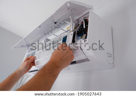 Maintenance of the air conditioner. A technician is cleaning the filter. View of the hands. Royalty-Free Stock Photo #1905027643