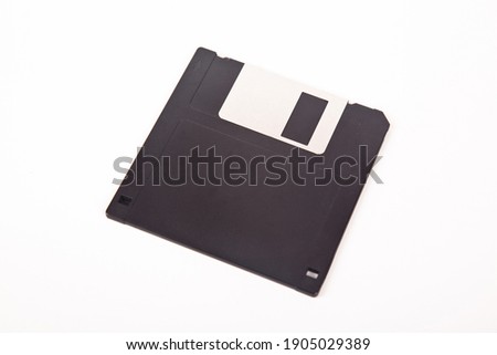 Old computer and data storage technology, black plastic magnetic floppy disk 3½ inches, isolated on white background
