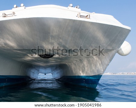 Detail of the bottom of a catamaran fast ferry moored in harbor, two parallel hulls, sunlight reflected from the water surface Royalty-Free Stock Photo #1905041986