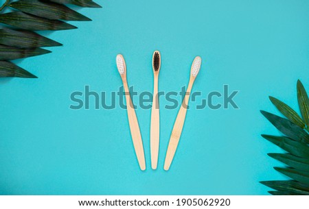 Bamboo toothbrushes and leaves on a blue background. The concept of nature-friendly toothbrushes. Flat lay. view from above. copy space
