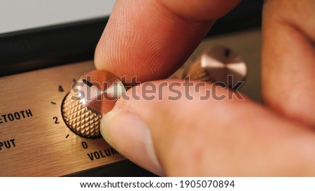 Hand adjusting volume control.Use hand to adjust the volume at the volume control button of the amplifier. Royalty-Free Stock Photo #1905070894