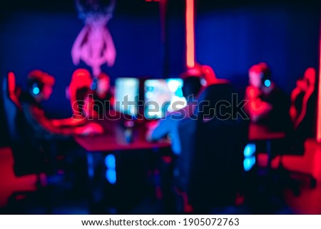 Blurred background professional team group gamer playing tournaments online games computer with headphones, red and blue.