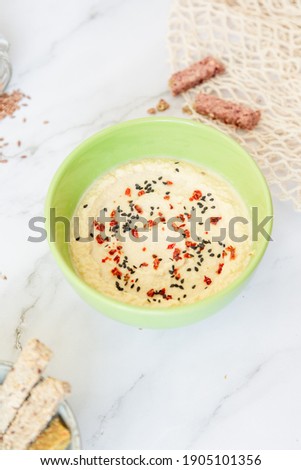 natural classic hummus with pepper flakes and sesame seeds and bread stick close up. light food photo of vegan vegetarian dishes with copy spaces. homemade recipe book