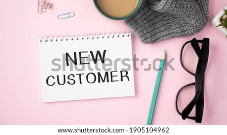 Notepad with text NEW CUSTOMERS on a pink background, near laptop, calculator and office supplies. Business concept.