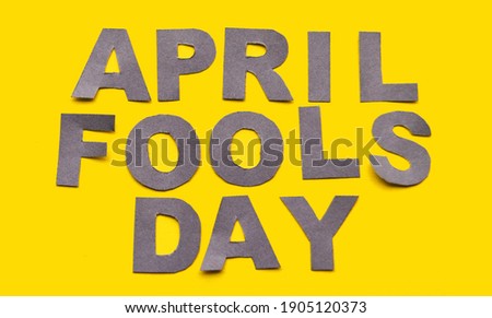 Image caption April Fools' Day made of grey paper letters on a yellow background close-up. High quality photo