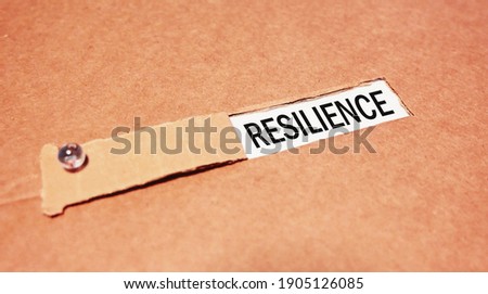 The text resilience. behind torn brown paper