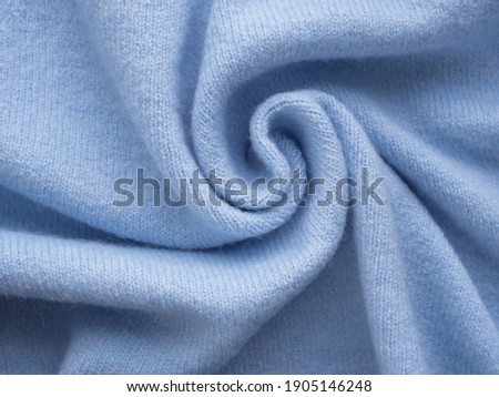 Comfortable style cloth. Simple knitted blue cashmere sweater. Pastel blue backdrop with curves, luxury fashion. Smooth elegant wrinkled fabric background. Abstract crumpled texture. Soft focus Royalty-Free Stock Photo #1905146248