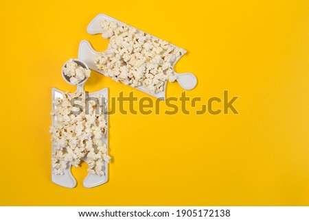 Puzzle dishes with popcorn on a yellow background. Making a family plan