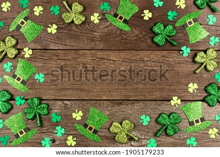 St Patricks Day shamrock and leprechaun hat frame. Overhead view over a rustic wood background with copy space.