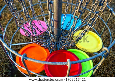 Disc golf basket with discs. The metal parts of the basket are selectively in focus. Royalty-Free Stock Photo #1905213421