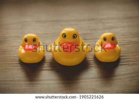 Concept of leader and follower. Selective focus of a small toy duck and big duck in a row on wooden background.