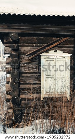 the facade of a dilapidated wooden house in a remote village in western Siberia