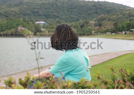 Young asian sitting near lake and mountain.