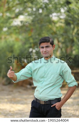 Young Indian Man showing thumps up over nature background.