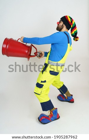 Holiday and fun concept. The clown firefighter holds a fire barrel in his hands, extinguishes the fire.