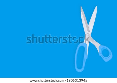 Barber scissors against blue background backdrop