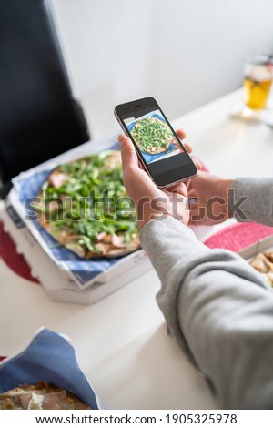 Blogger Man takes a picture with his smart phone of the pizza he is sharing with friends, for his followers on social networks.Copy space