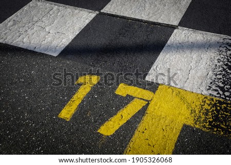 Grey asphalt road, yellow painted number seventeen on grey street, yellow lines like a corner on the road, space for text 
 Royalty-Free Stock Photo #1905326068