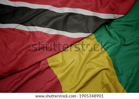 waving colorful flag of guinea and national flag of trinidad and tobago. macro