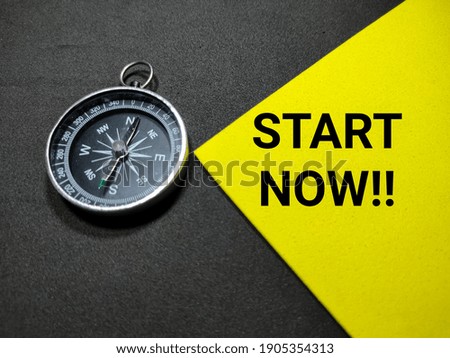 Selective focus.Text START NOW with compass on a yellow and black background.Business concept.Shot were noise and grain.